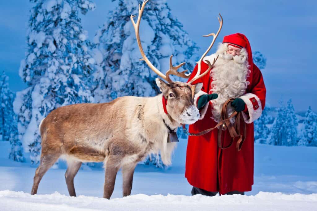 Santa Claus with reindeer in a snowy winter landscape.