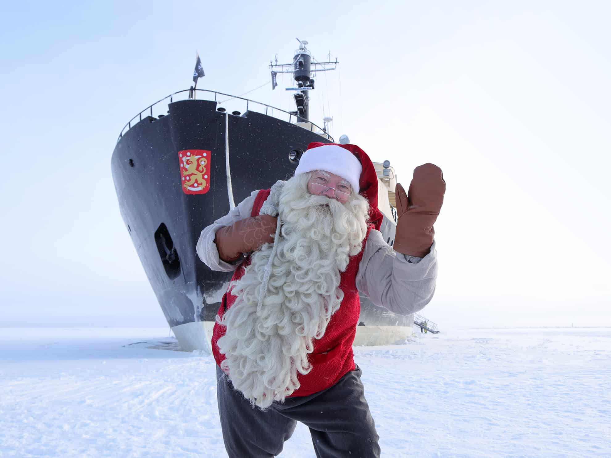 Santa Claus in a red suit with a white beard on icy Arctic landscape.